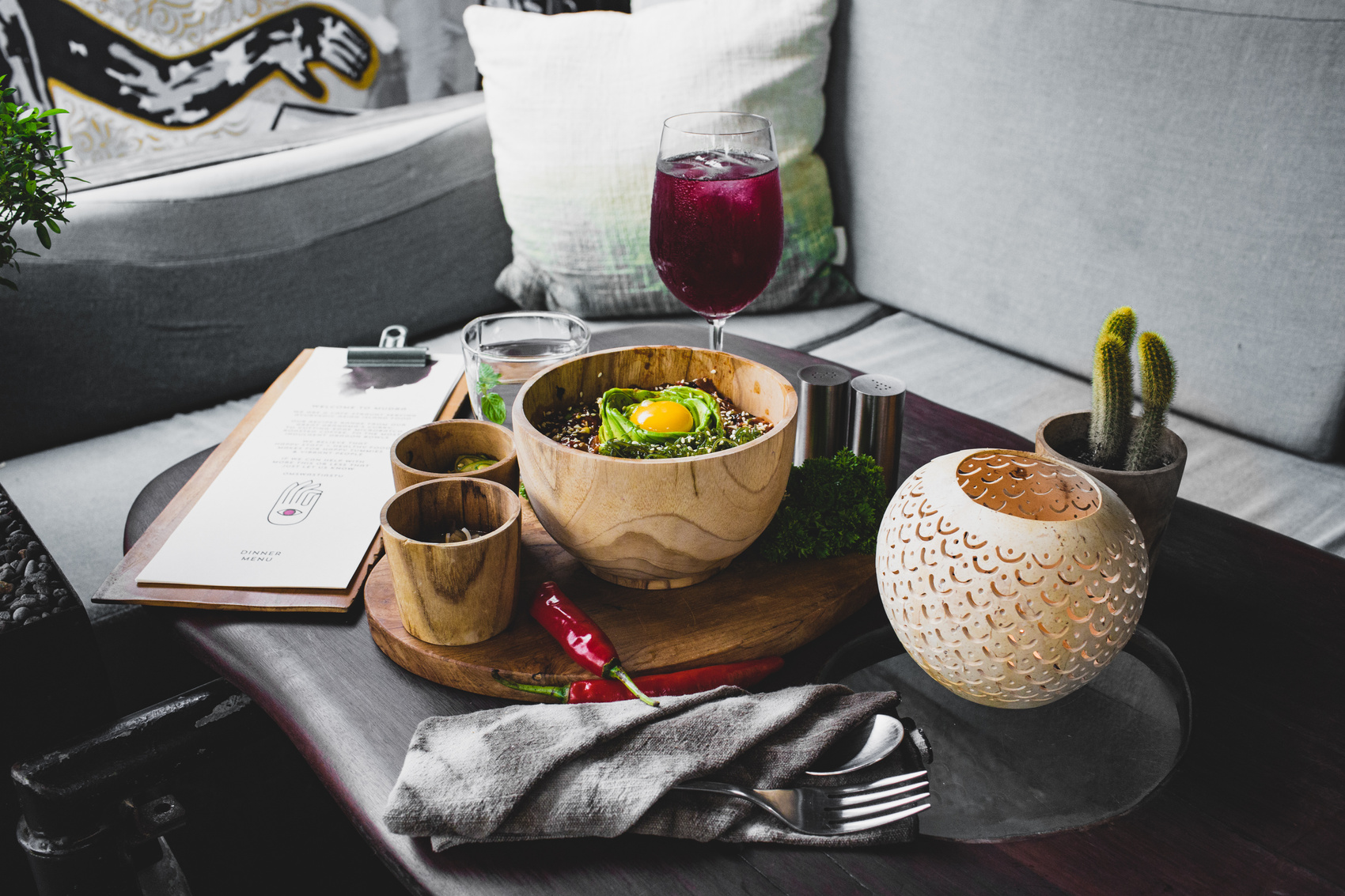 Serving of oriental food in wooden dishes with drinks on table of modern cafe